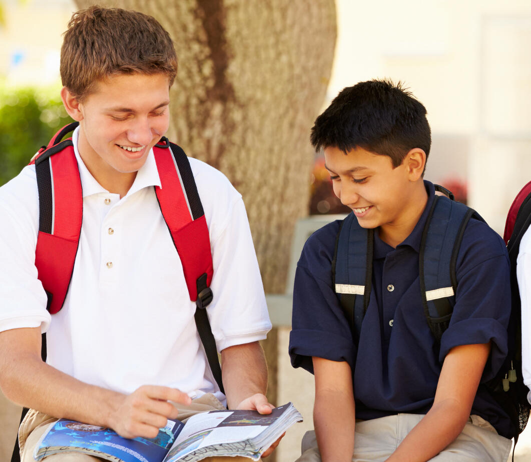 Two boys at school looking at a book